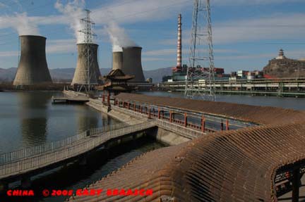 Cooling towers and stacks of Capitol Steel, built around Ming Dynasty Pagoda Shi Jing Shan on hill.  Steel company built pavillions in cooling pond. West Beijing.